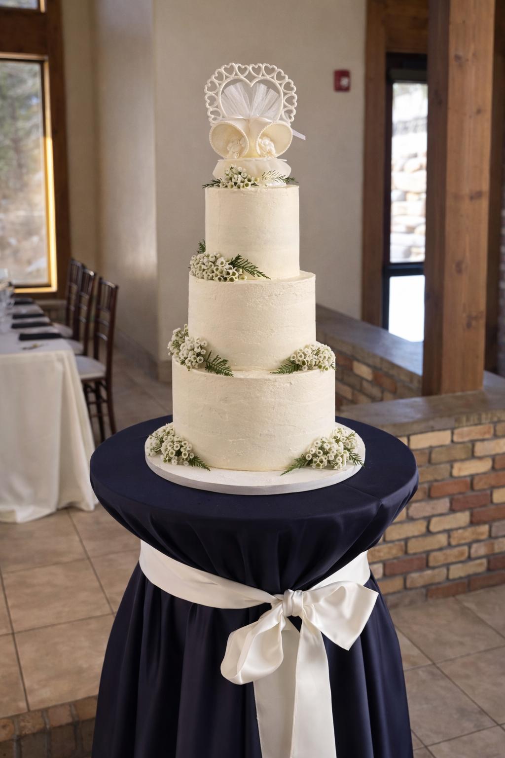 Four-tiered white cake with baby's breath and heart topper