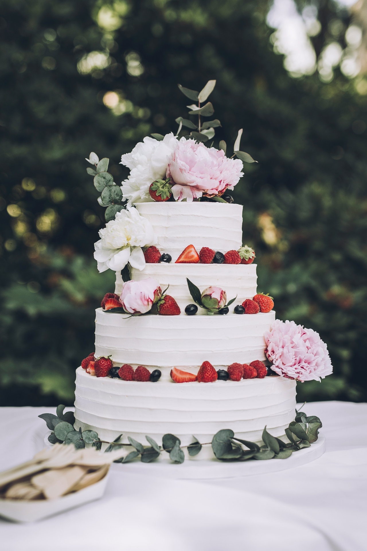 Four-tiered cake with peonies, berries and eucalyptus