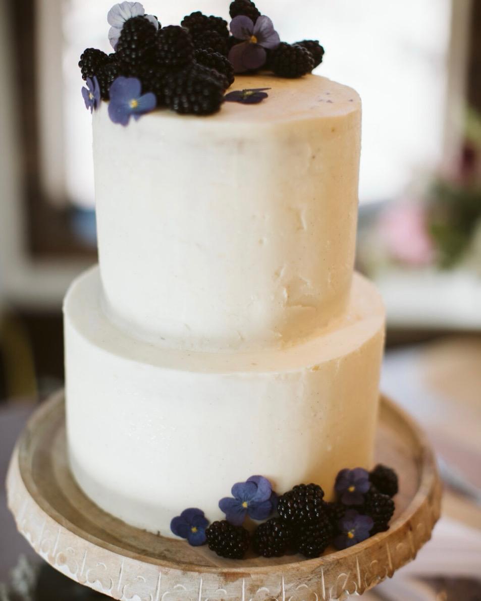 Two-tiered cake with blackberries and purple pansies