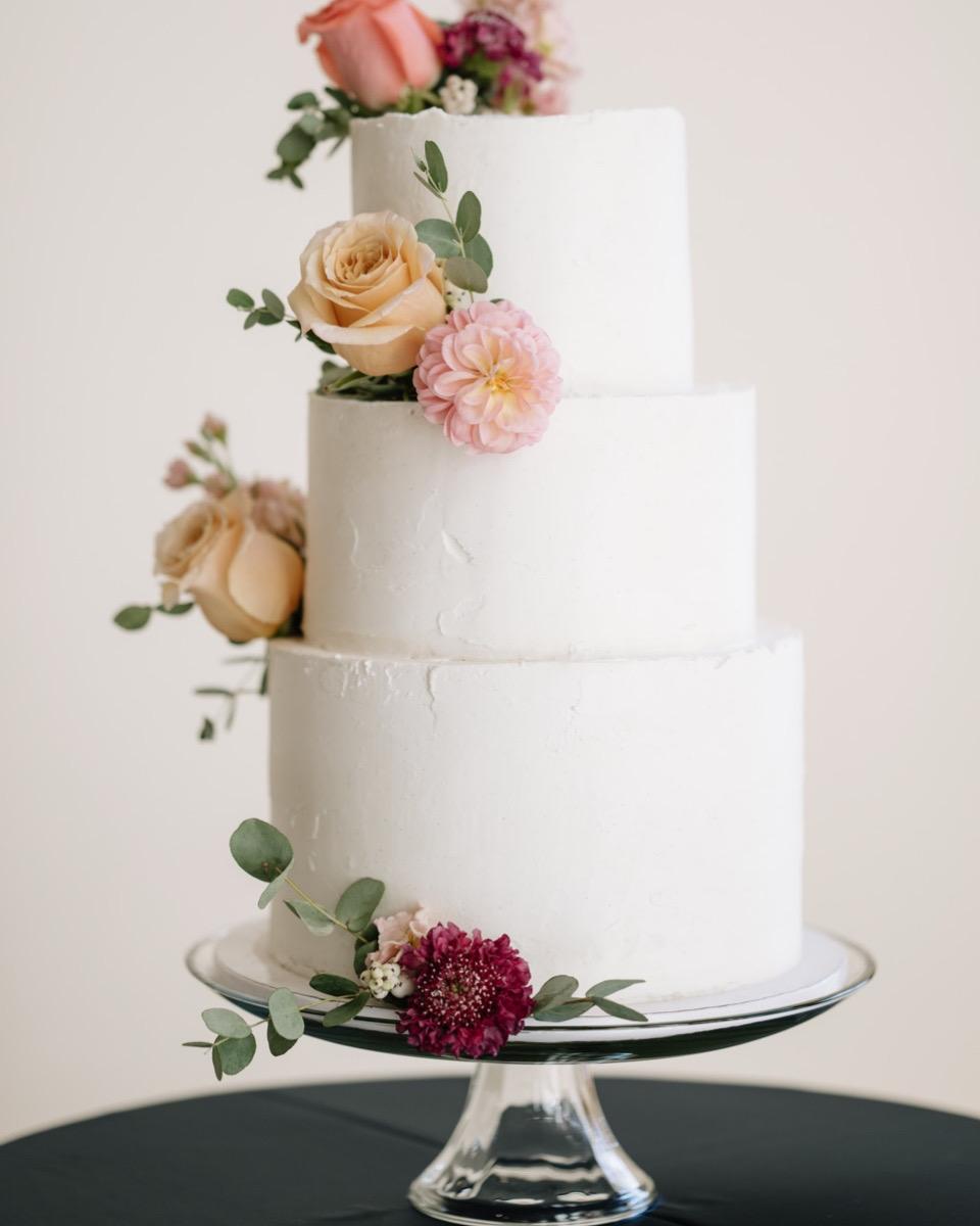 Three-tiered cake with peach roses and pink dahlias