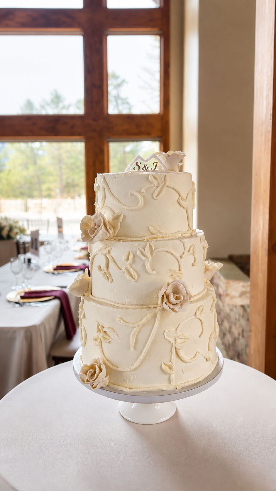 Three-tiered ivory cake with vine scrollwork and sugar roses