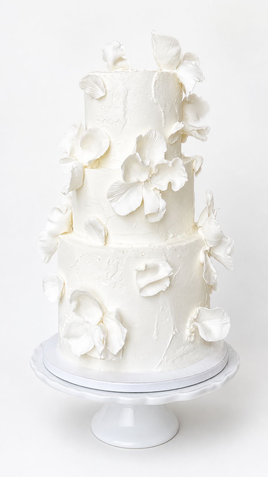 Three-tiered white textured cake with sugar petals